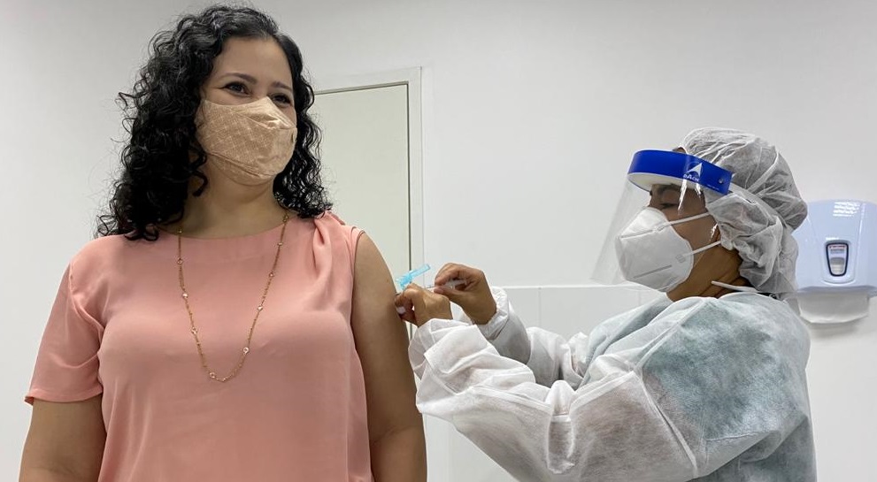 mulher de máscara sendo vacinada